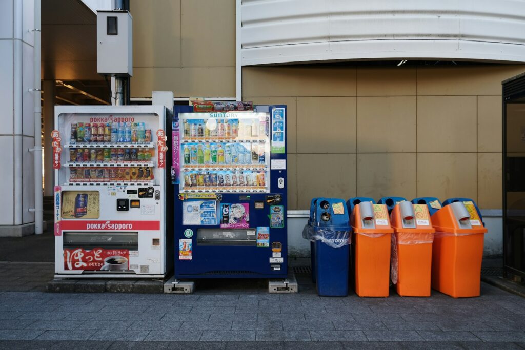 a vending machine next to a row of orange and blue bins