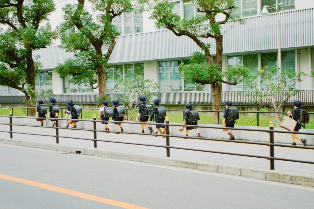 Students in uniform walk along a sidewalk.